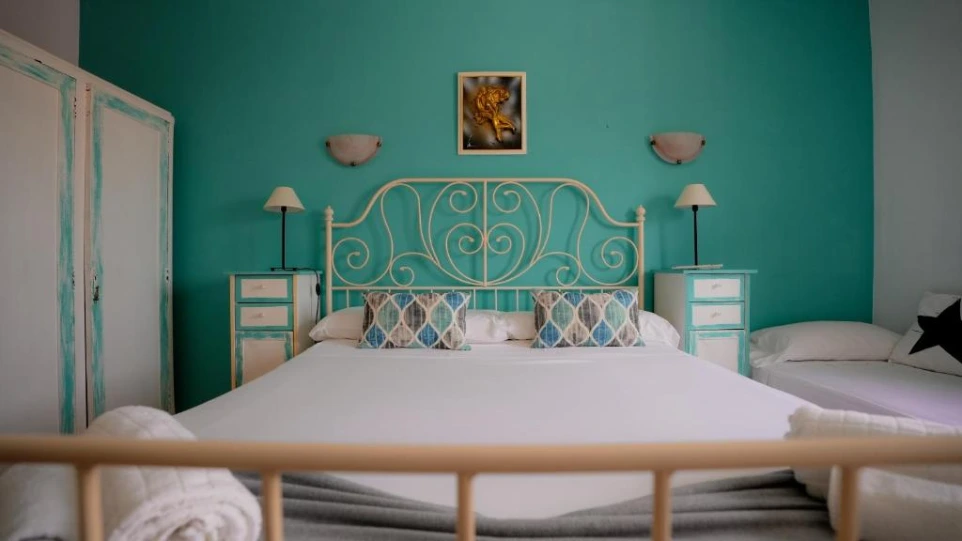 Cama y almohadones blancos con fondo de pared azul claro