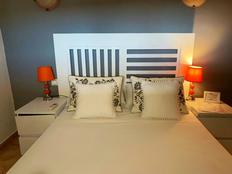 cama con acentos y almohadonesblancos y lamparas naranjas